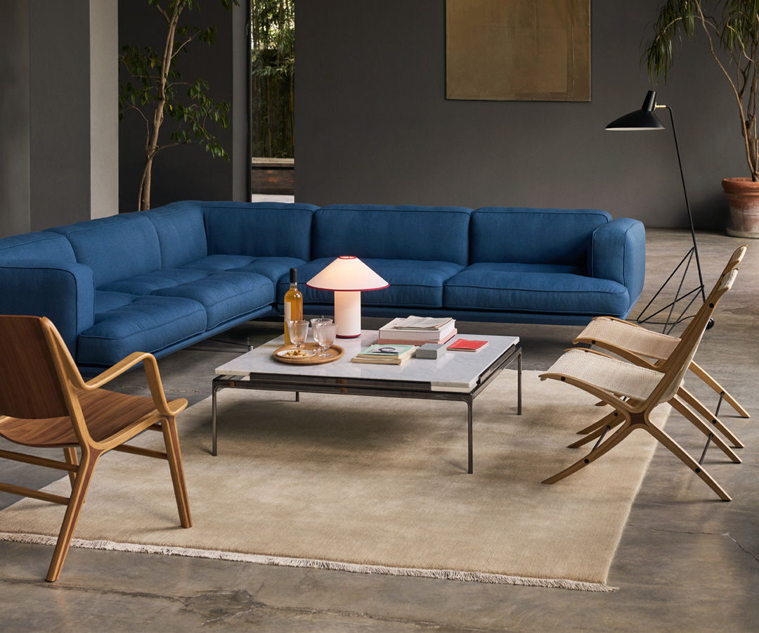 Modern living room with &tradition blue sectional sofa, coffee table, and stylish chairs.