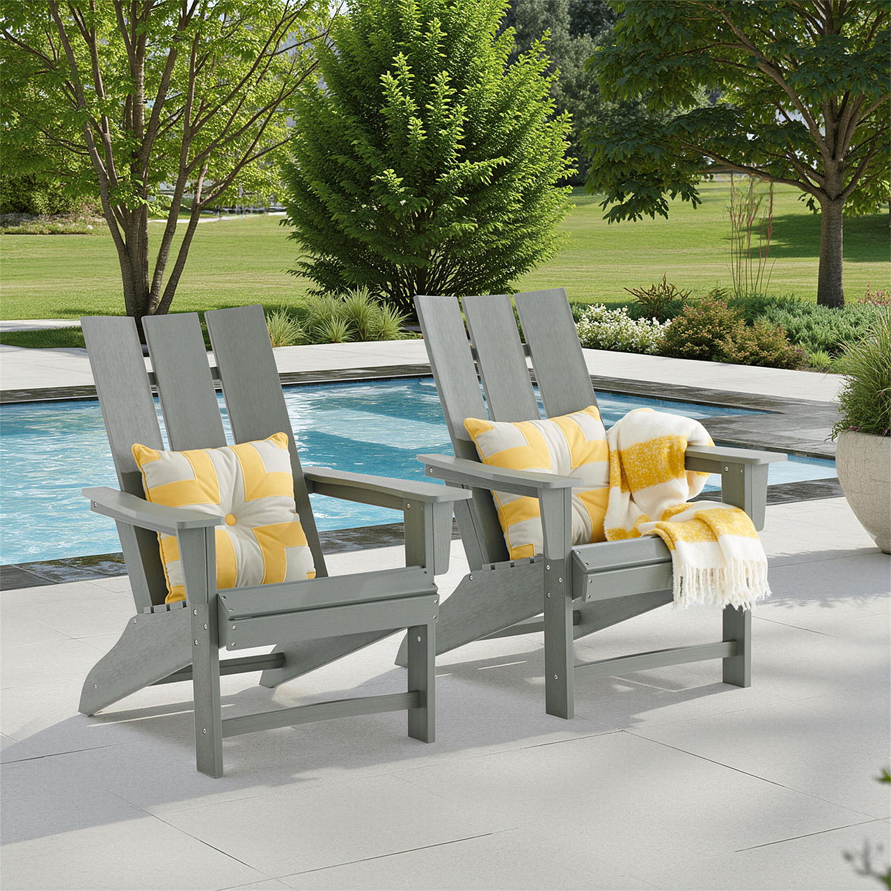 Two gray Adirondack chairs by a pool, adorned with yellow pillows and a blanket.