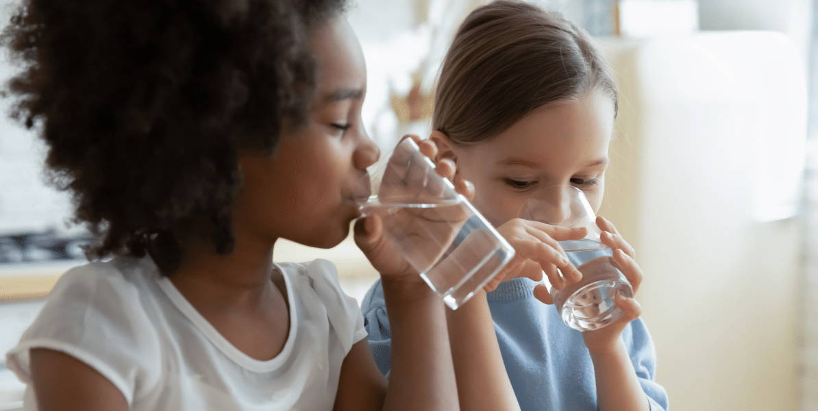 Dos niñas beben agua potable filtrada