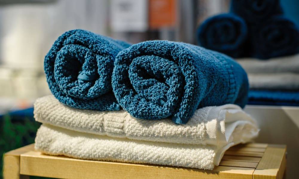 blue towels rolled up on top of folded white towels