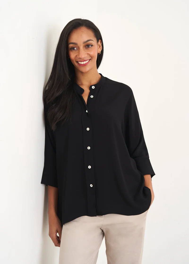 A model wearing a black crepe button down relaxed fitting shirt with 3/4 sleeves and mother of pearl buttons