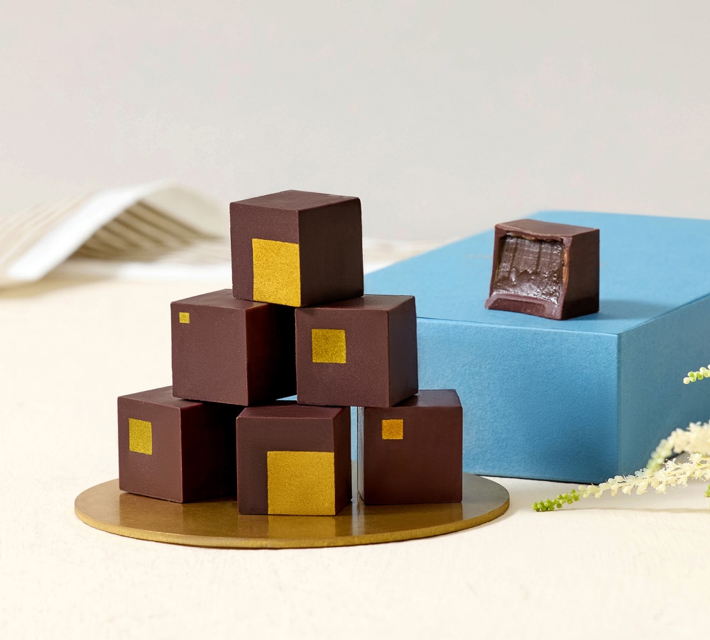 Assorted chocolate cubes on a light background with a blue box.