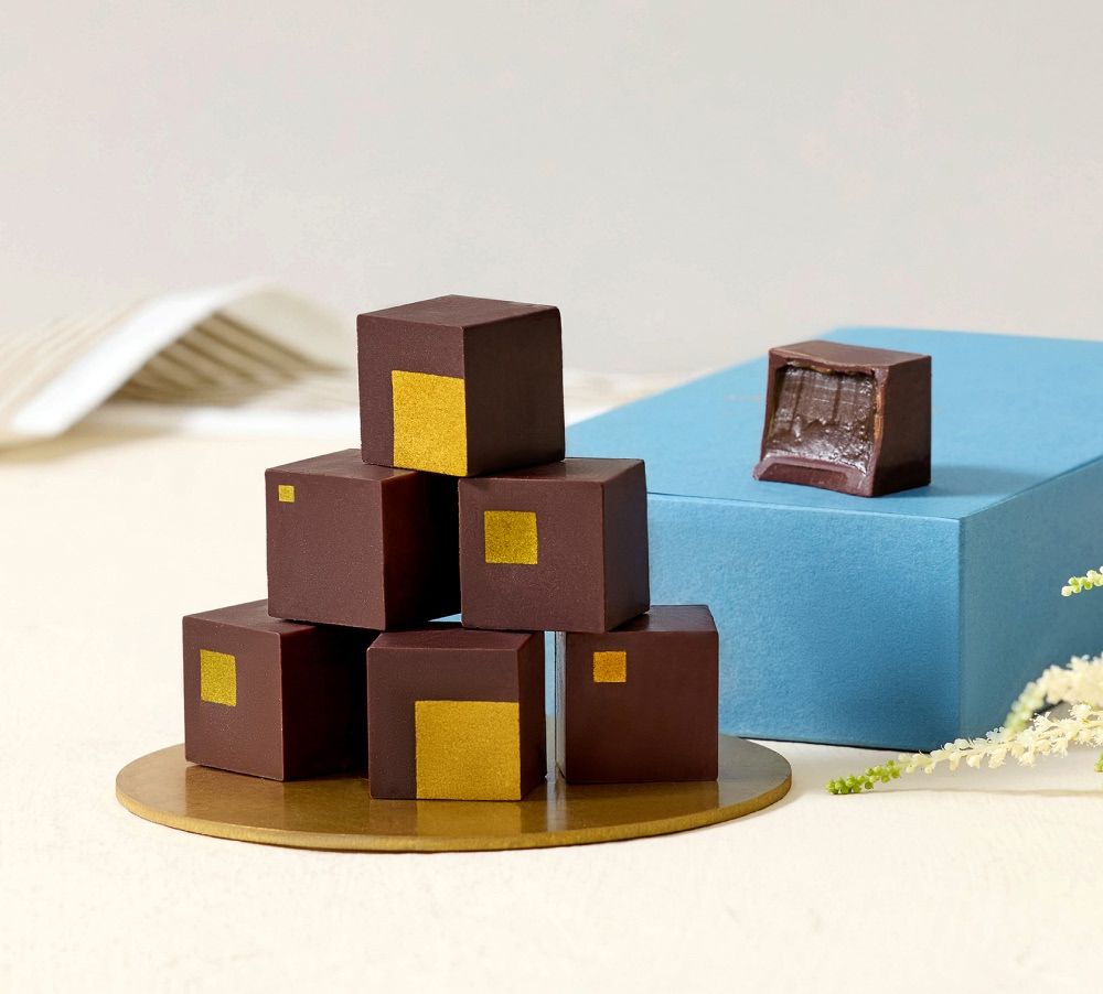 Assorted chocolate cubes on a light background with a blue box.