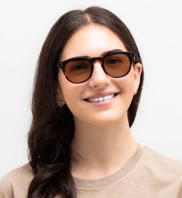 Woman wearing round transition lens glasses in brown tint
