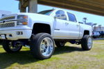 White lifted 2014 Chevrolet Silverado 1500 with chrome wheels and blue suspension Ethan's Outlaw train horn install thumbnail