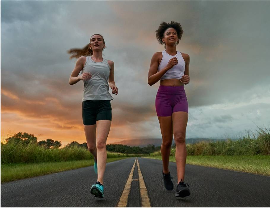 Two women road running in Nathan apparel with a sunset as the backdrop