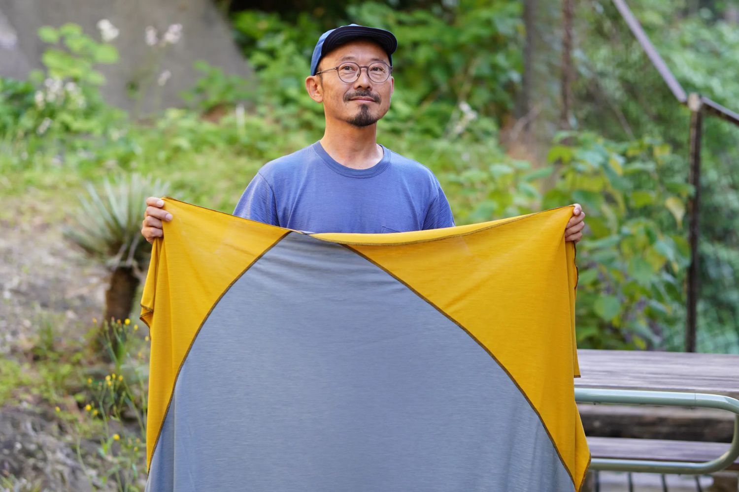 Person holding a yellow and gray fabric outdoors in a natural setting.