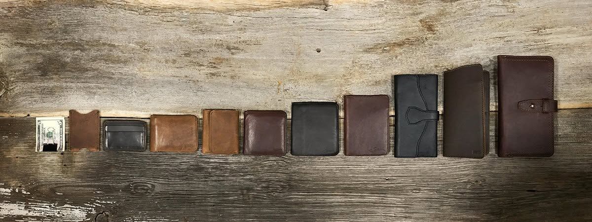 Leather wallets in different sizes, styles, and brown tones arranged on a rustic wooden surface beside a folded dollar bill.