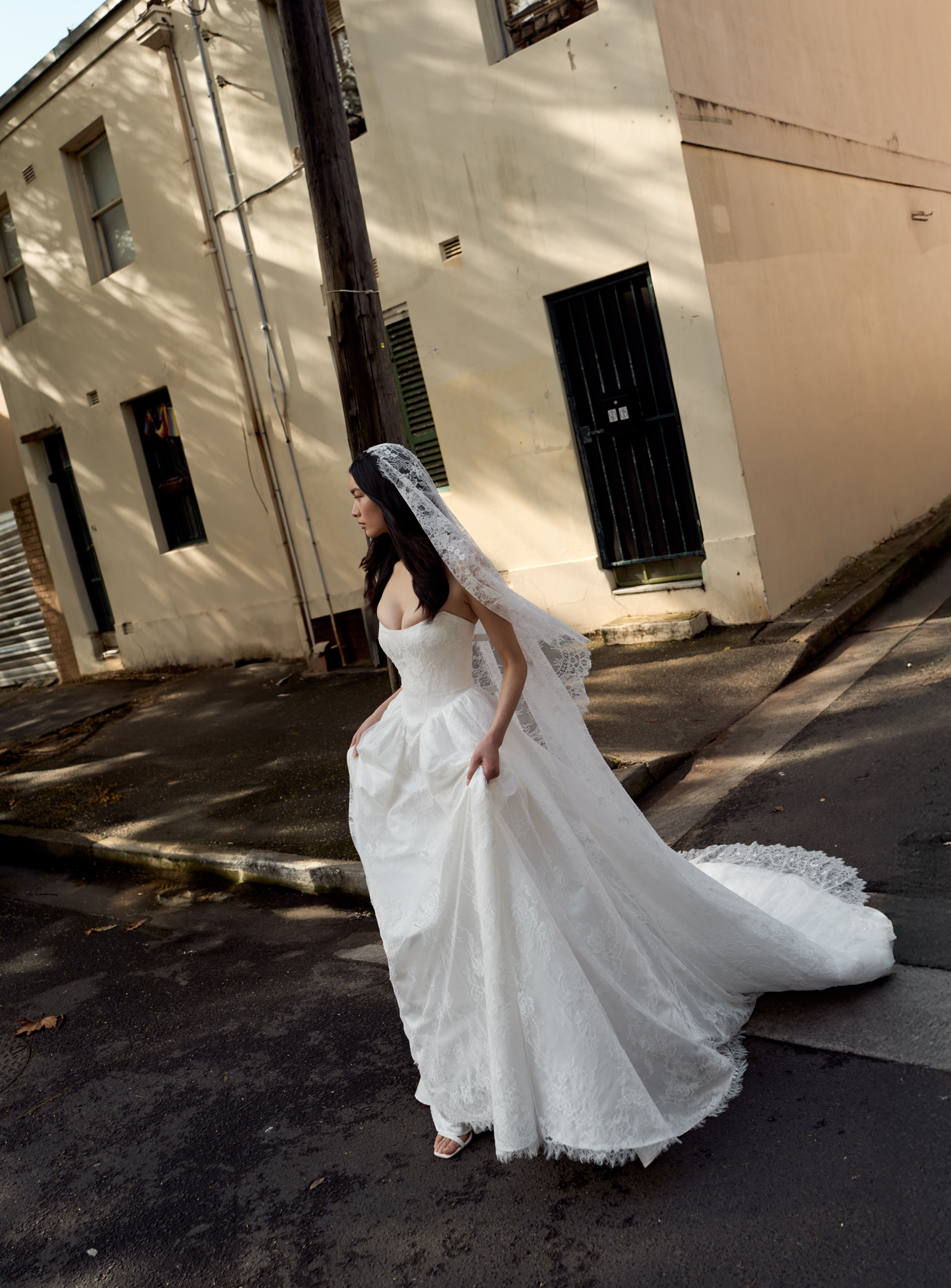 Bride in a white wedding dress walking on a street.