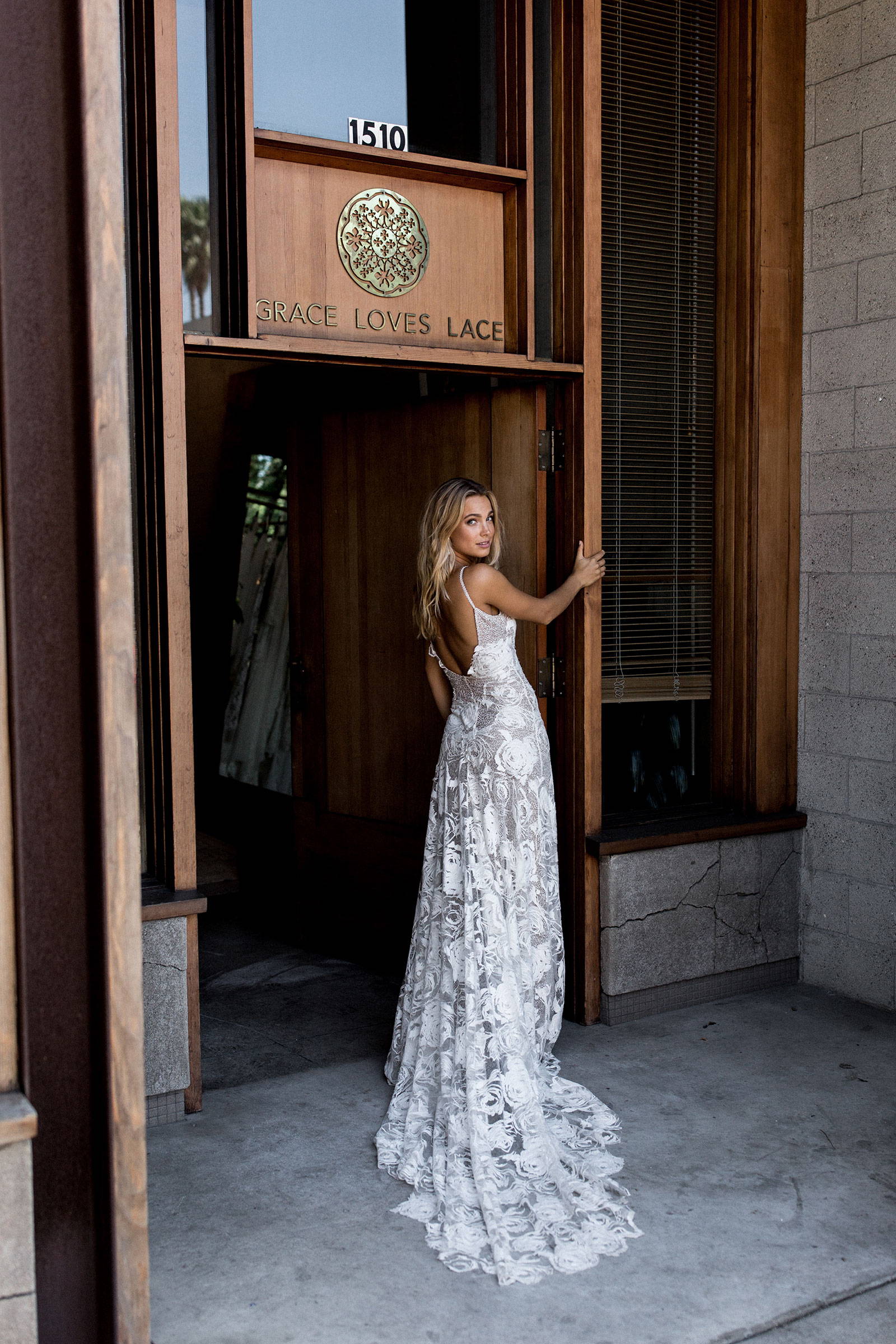La novia Grace Loves Lace con el vestido de novia Rosa en la entrada de la sala de exposiciones de Los Ángeles