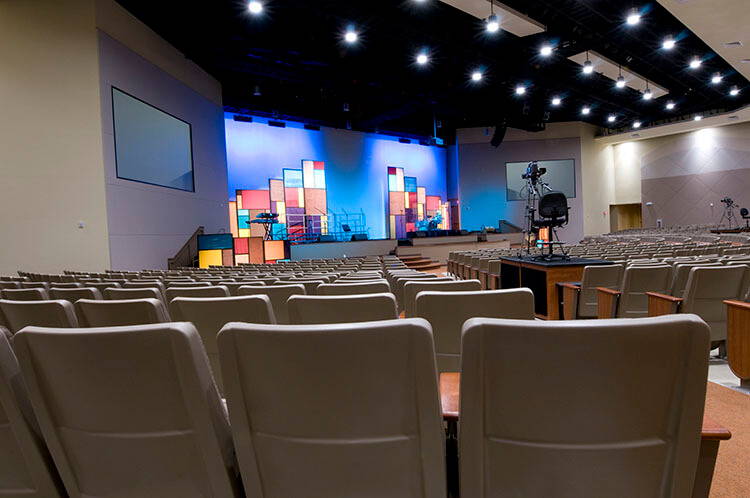 Worship auditorium with stage, screens and ceiling lighting