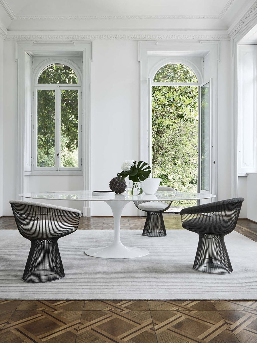 Modern dining area with a round table and stylish chairs by large windows.