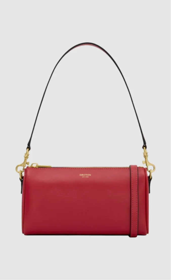 Red leather handbag with a black strap and gold hardware.