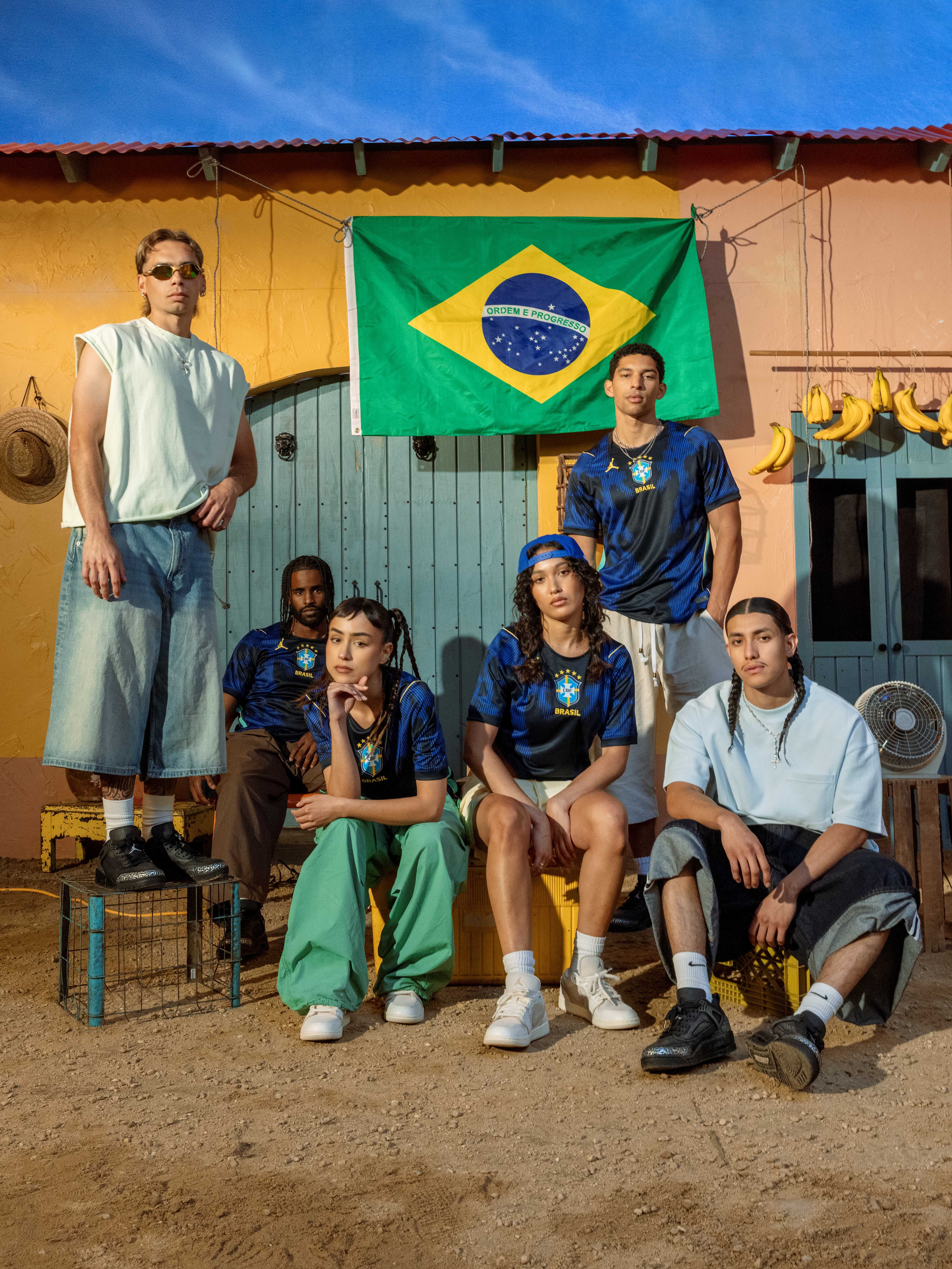 Group of young people posing in front of a Brazilian flag.