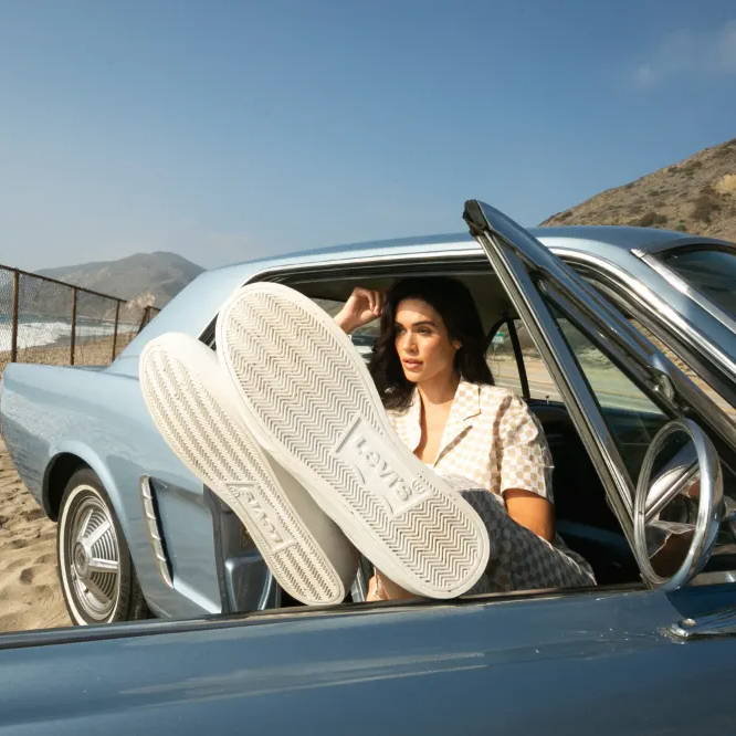 female model sitting in car with feet out window wearing levi's shoes