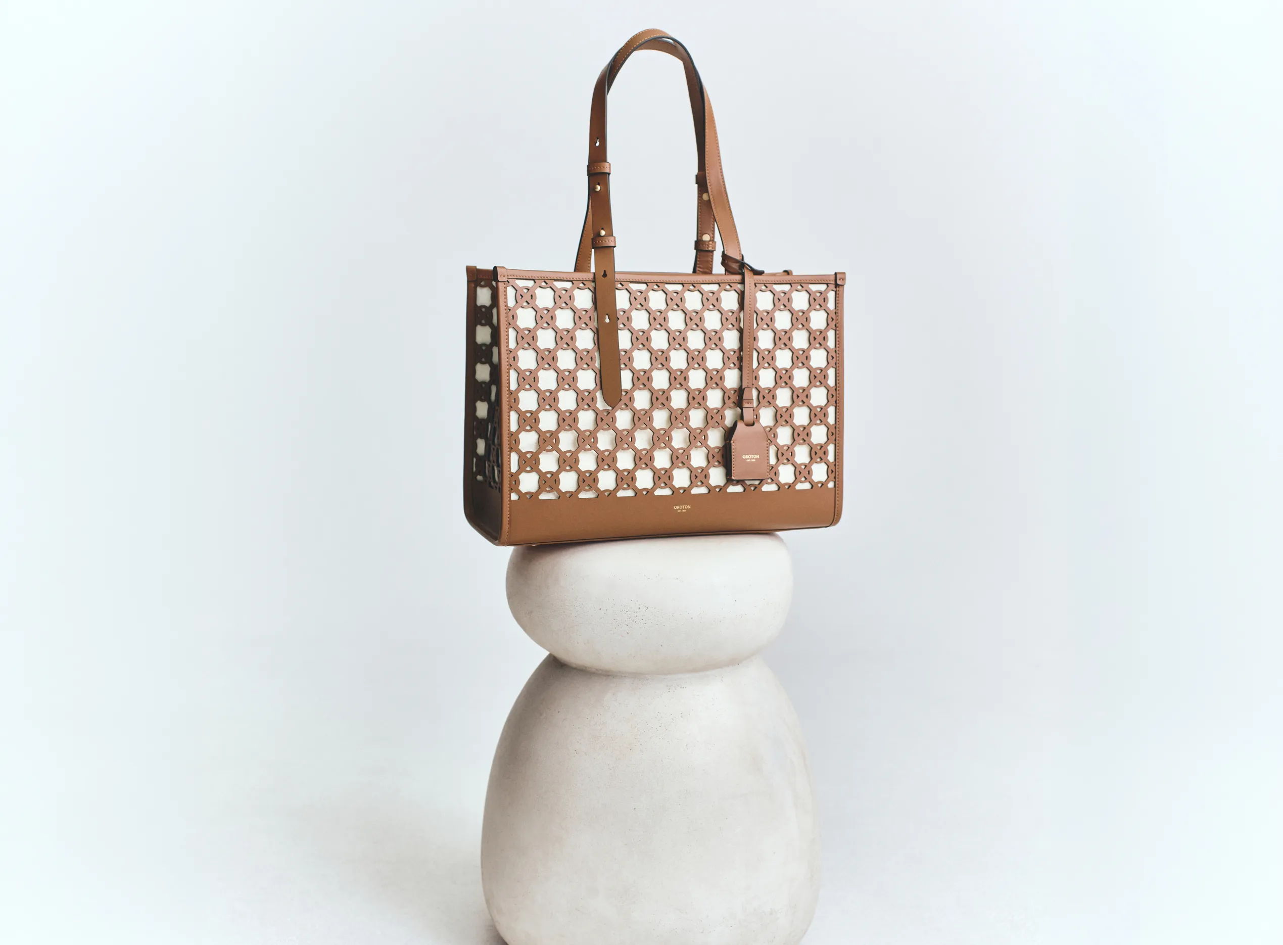 A stylish tote bag displayed on a smooth stone pedestal.