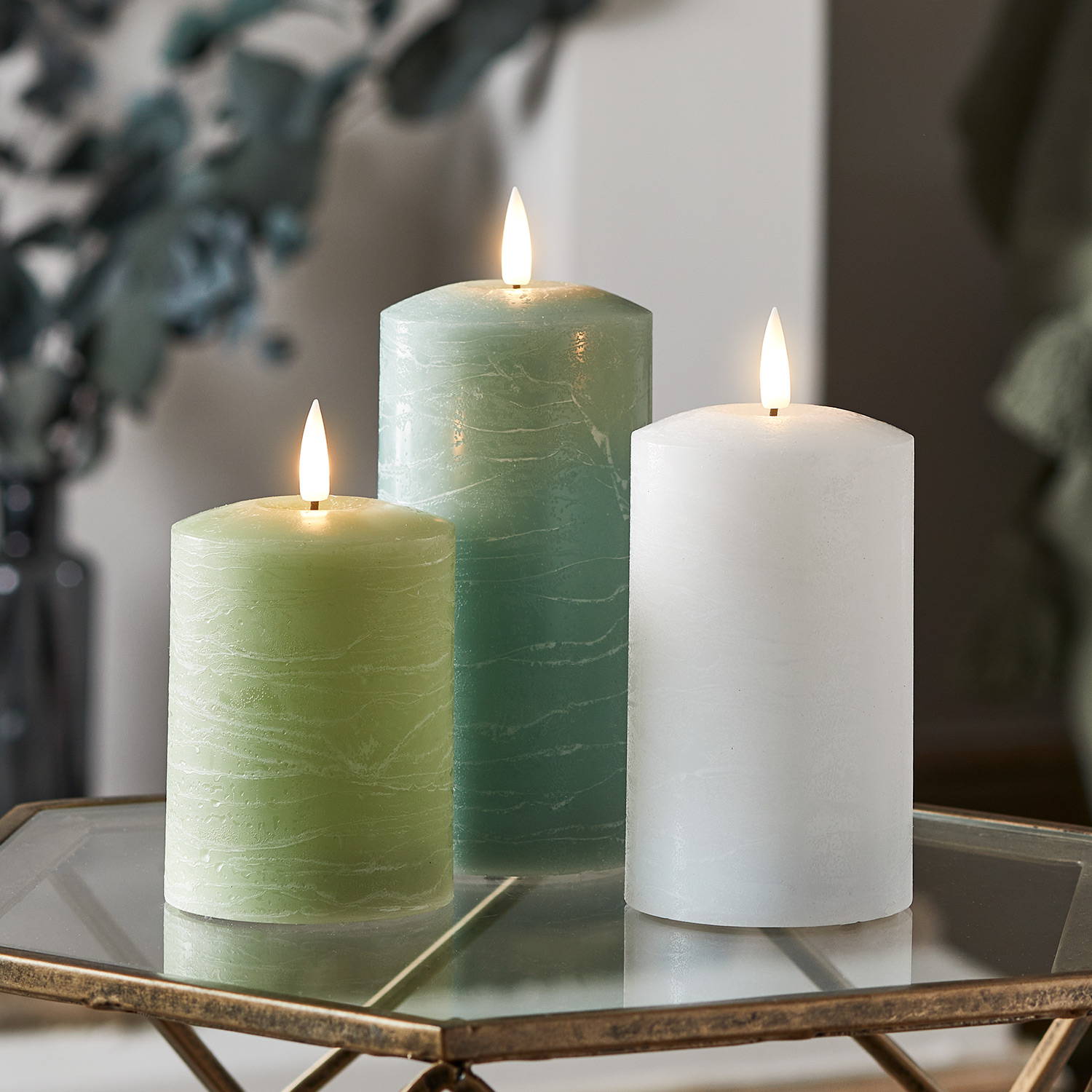 3 green and white LED candles on a side table in a living room.