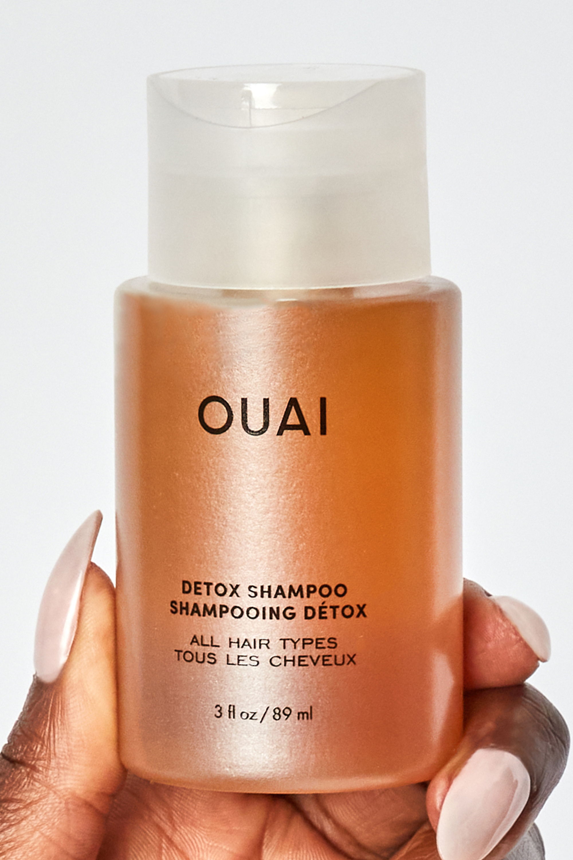 Bottle of OUAI detox shampoo held in hand.