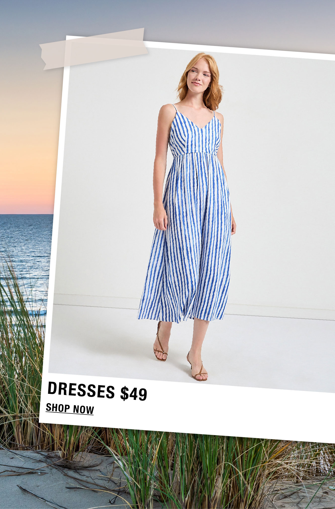 Woman in a striped dress standing on a beach at sunset.