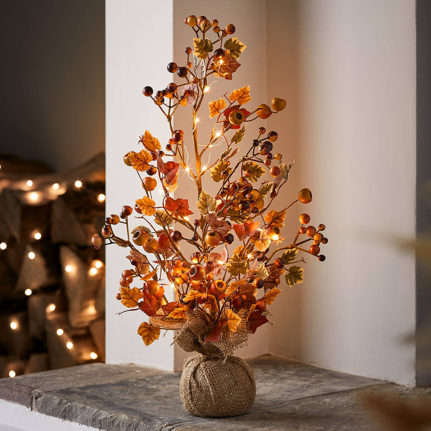 Harvest autumn twig tree with a burlap base, stood on a fireplace