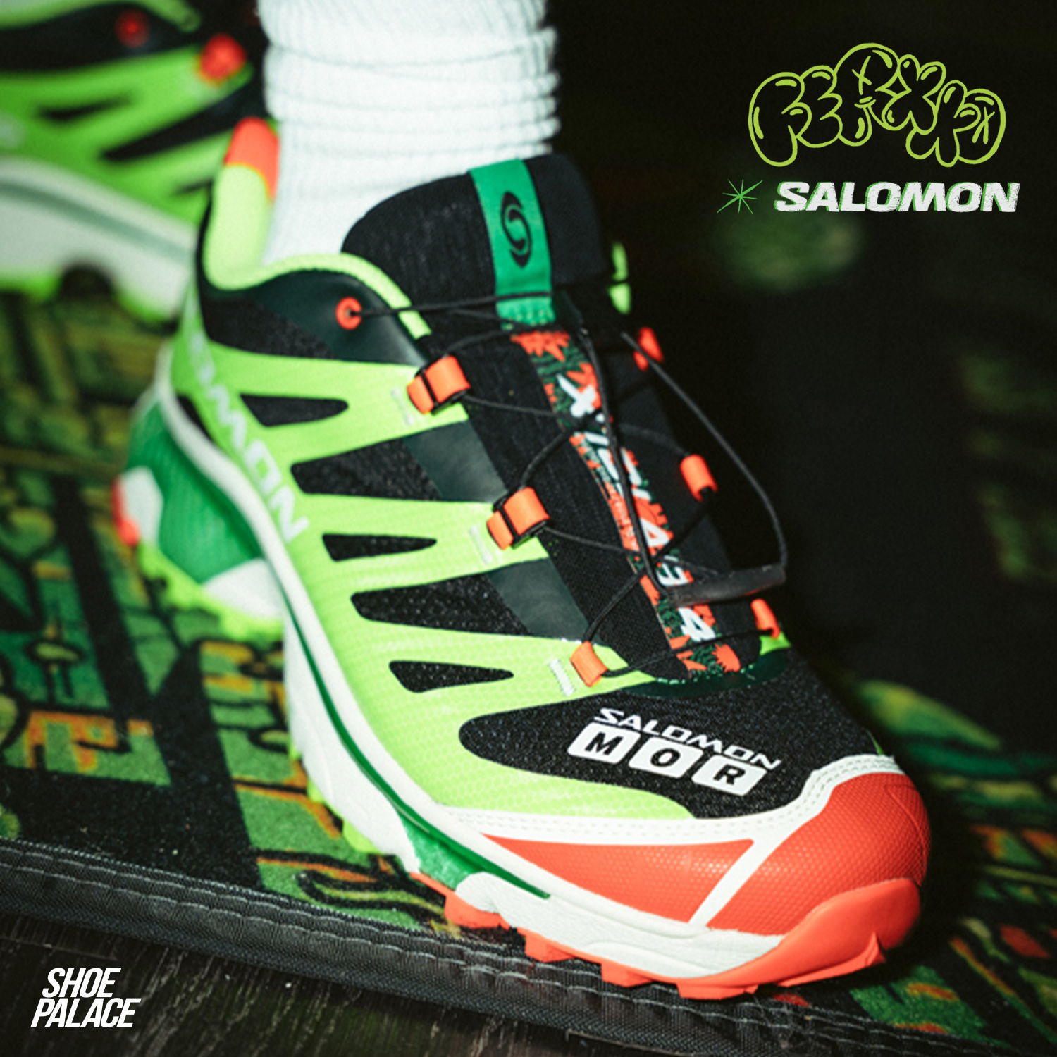 A close-up of a black, green, and orange sneaker by Salomon.