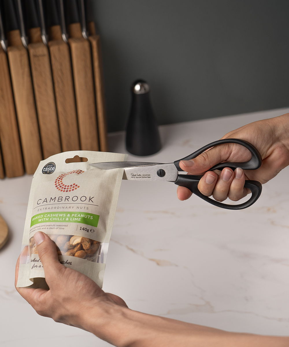 Person using Signature Scissors to open a package of nuts.