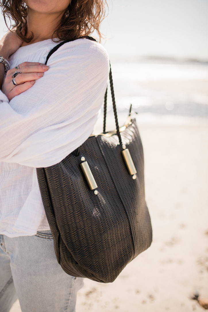 woman wearing black basketweave zip tote bag