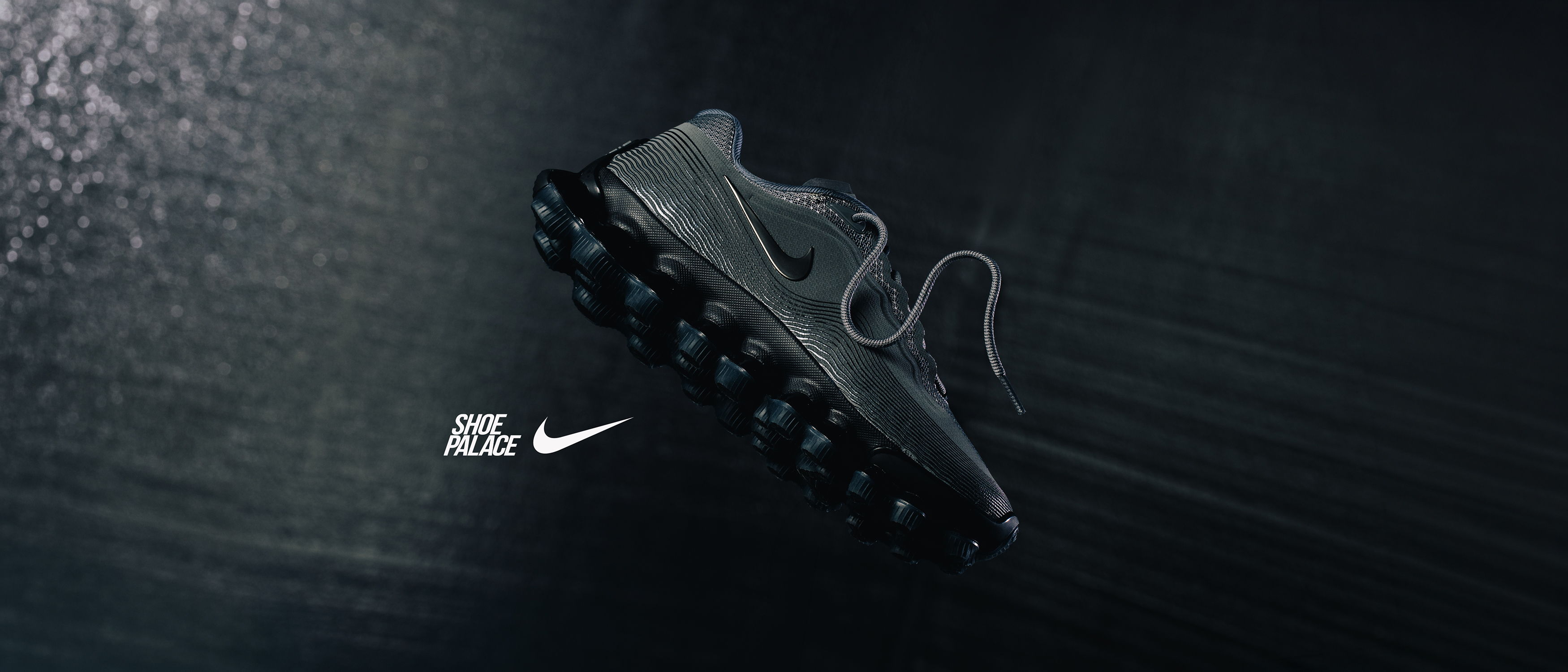 A black Nike sneaker on a dark surface.