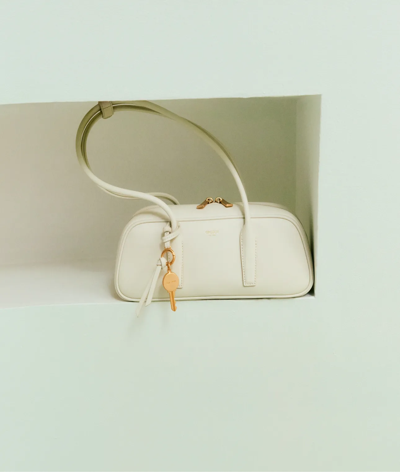 A white handbag with a key hanging from it.
