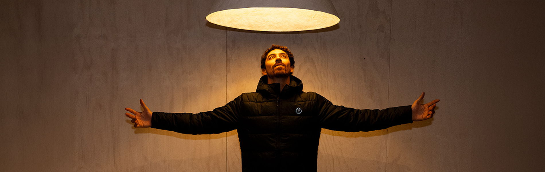 Person with arms outstretched beneath a glowing overhead light.