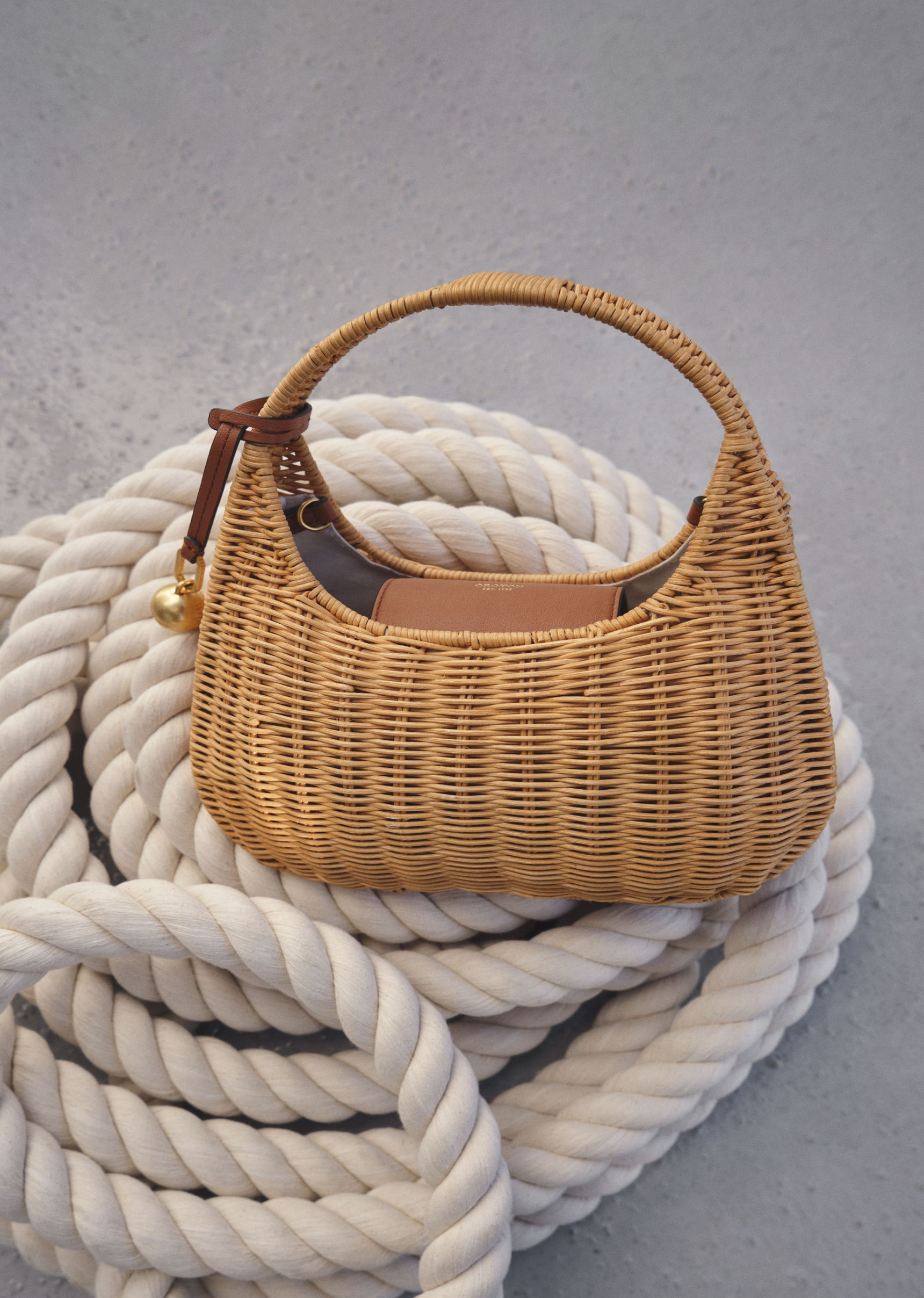A woven handbag resting on a coiled rope background.