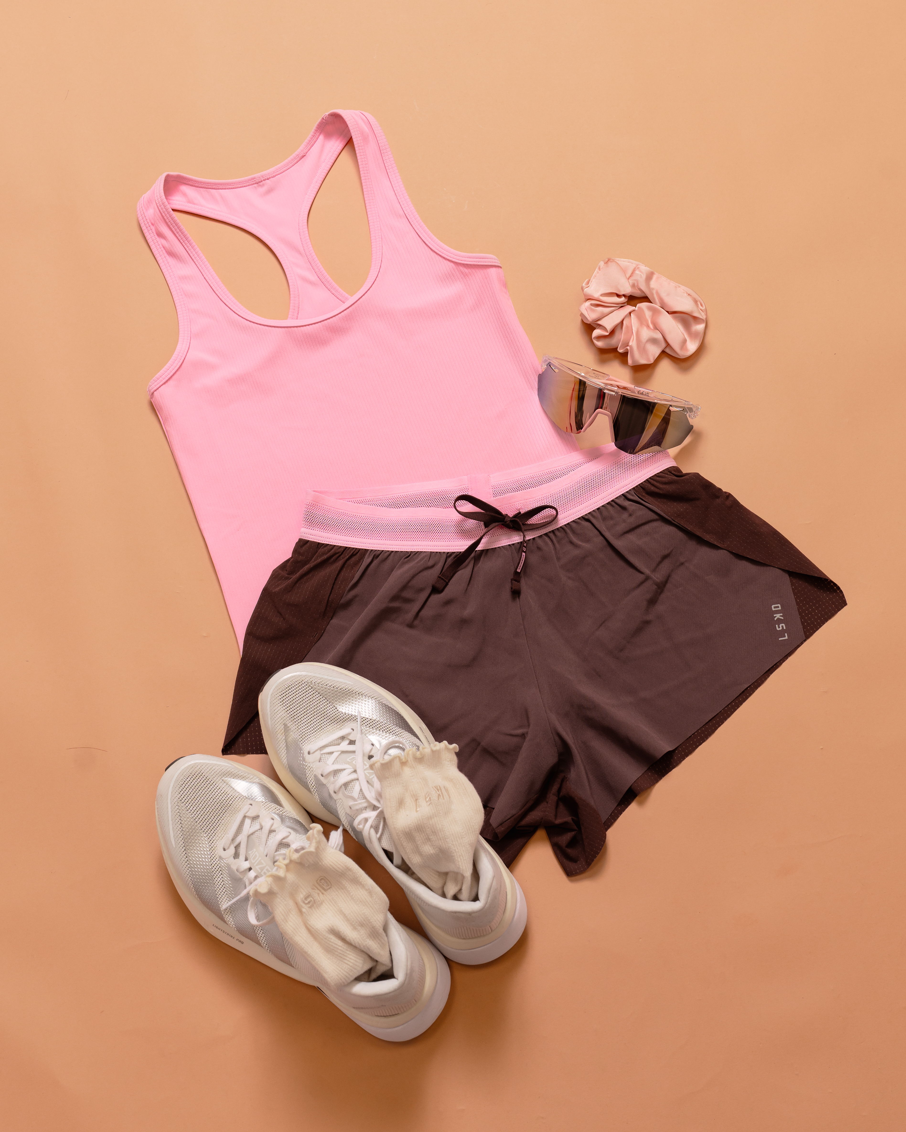 Athletic outfit including a pink tank top, brown shorts, and shoes.