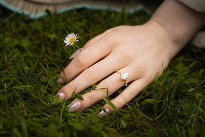 hand with engagement ring in grass