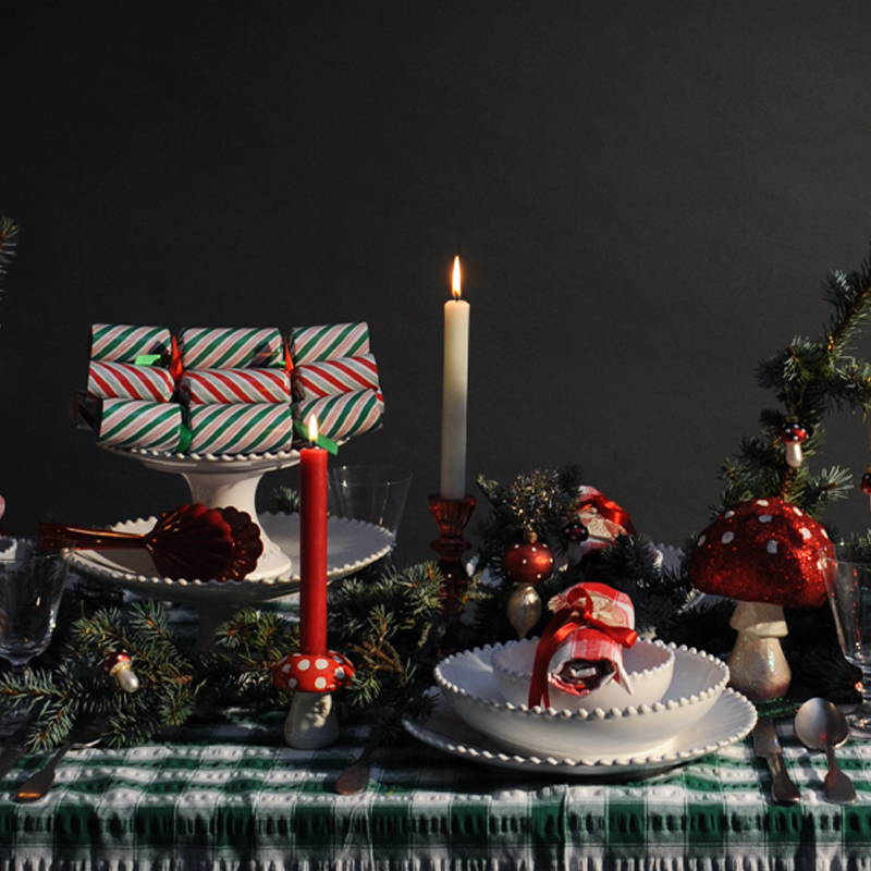 A green, red and white laid christmas table with christmas tree greenery. 