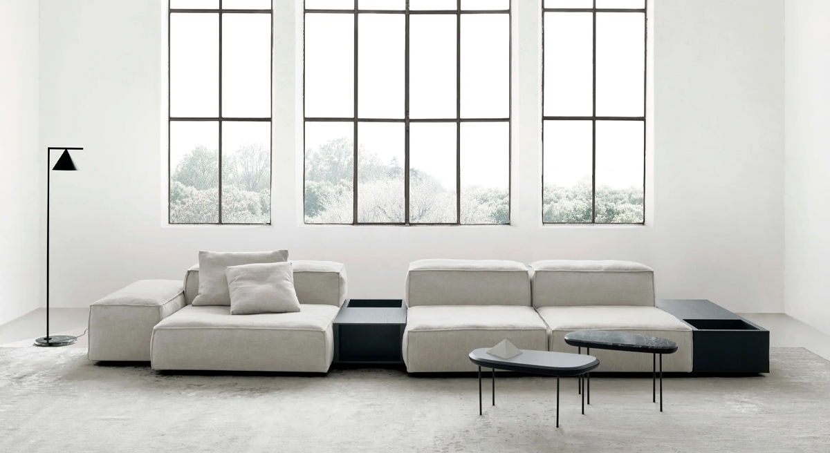 Modern living room with white sectional sofa, black coffee table, and large windows.