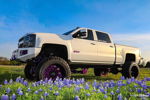 White lifted Silverado 2500HD in bluebonnet field thumbnail