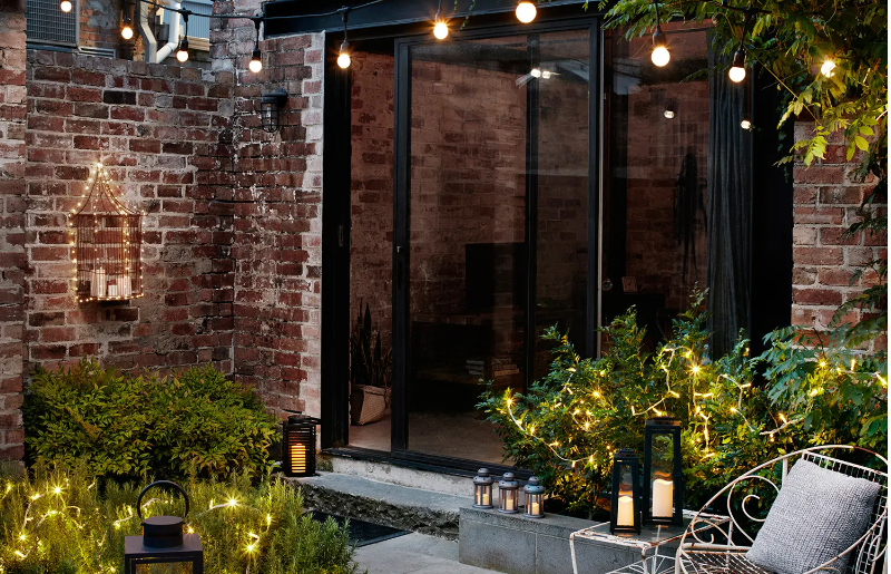 Garden setting with festoons, lanterns and fairy lights among the plants.