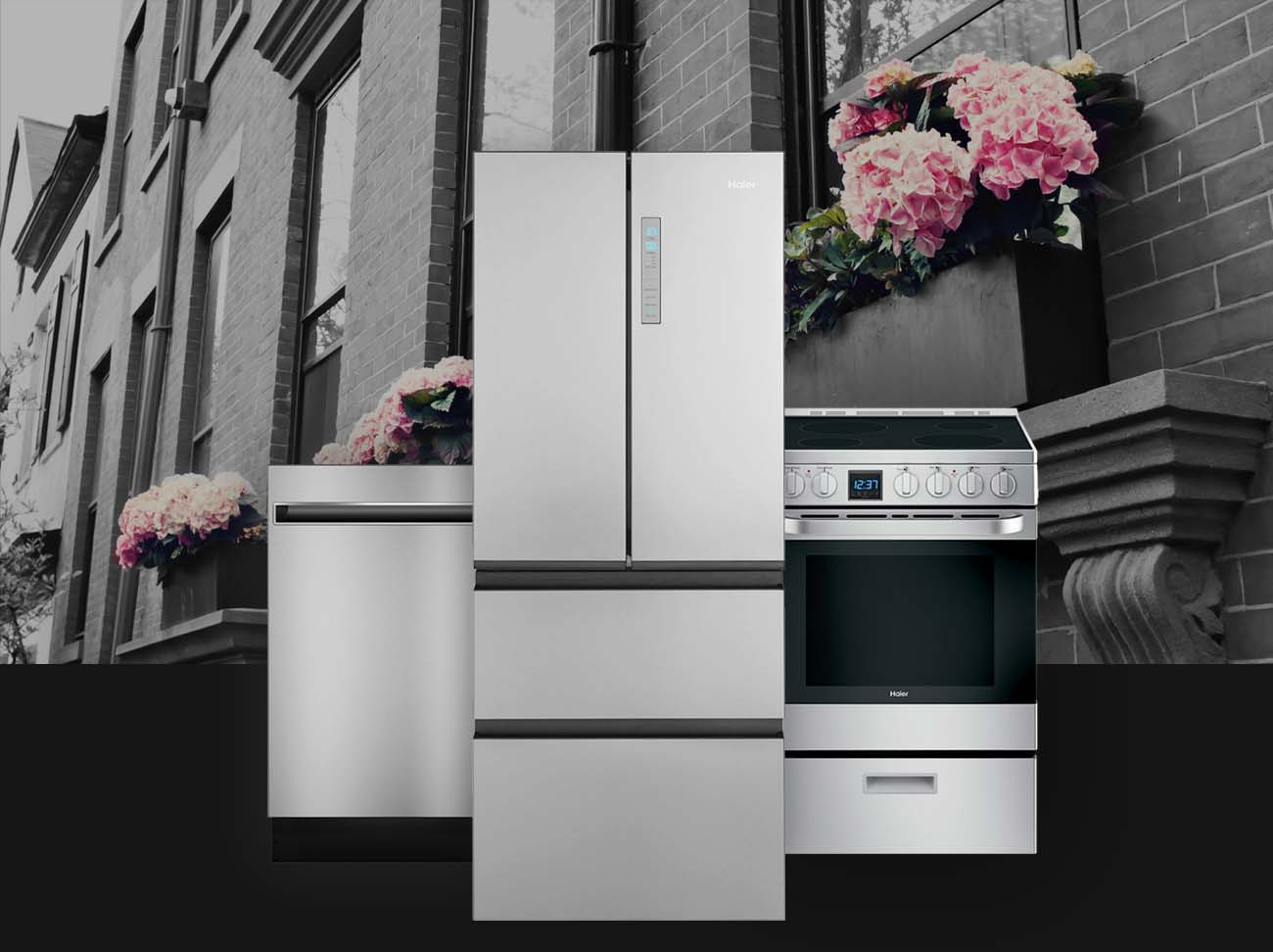  Haier small-space kitchen appliances layered over a background image of a downtown building with fresh spring flowers in large window garden boxes.