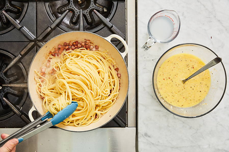 Cooked bucatini added to pan with pancetta.