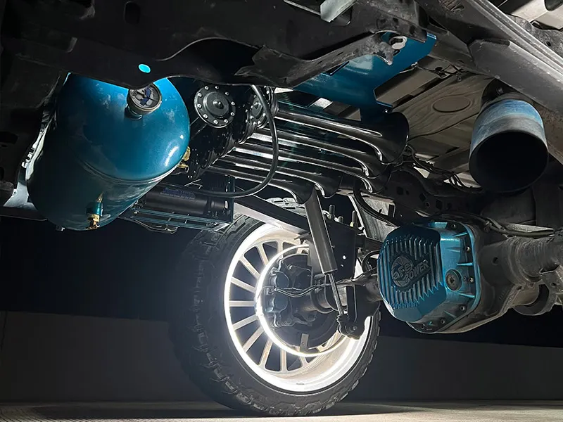 Undercarriage view of Holden's Ford F250 showing blue air tank, train horn trumpets, and aFe POWER differential cover
