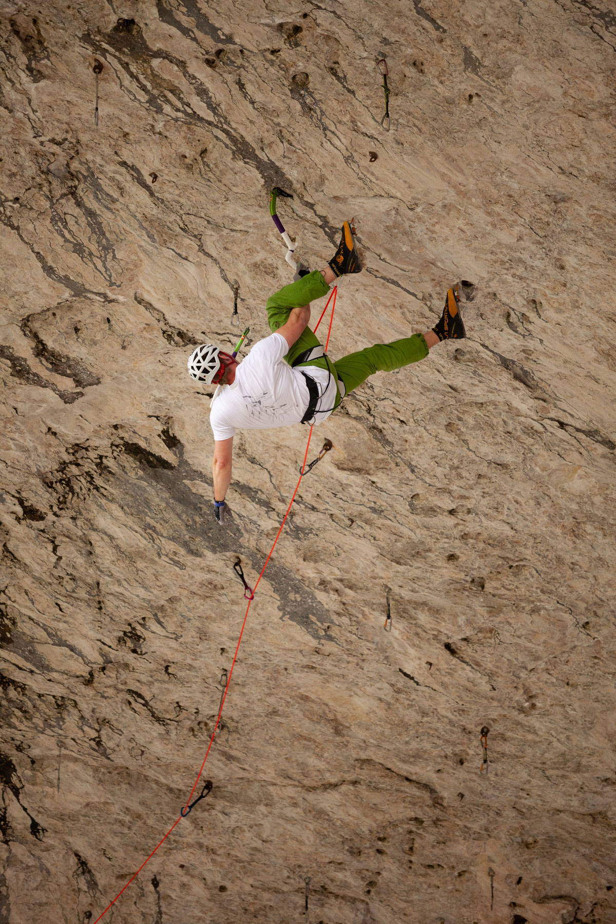Rock climber climbing upwards along the tan rocks