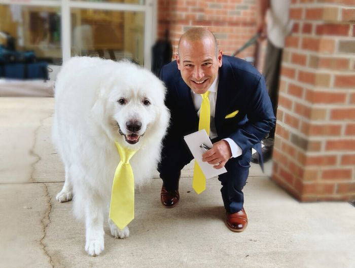 Groom wearing a matching yellow necktie with his dog