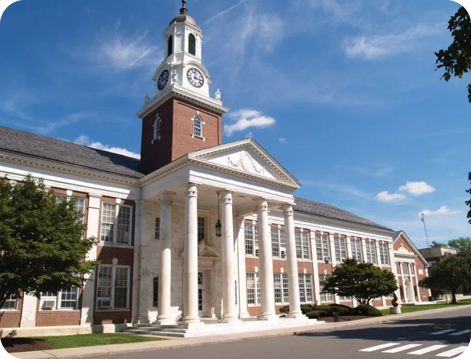 Historic building with a clock tower and columns under a blue sky.