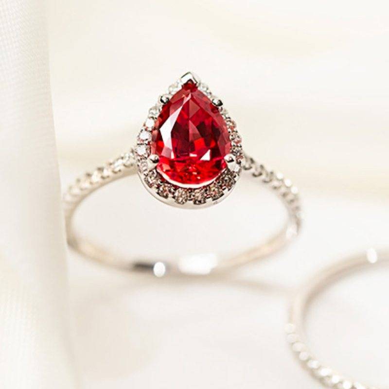 Custom built halo diamond accented white gold engagement ring with tear drop lab grown ruby center stone