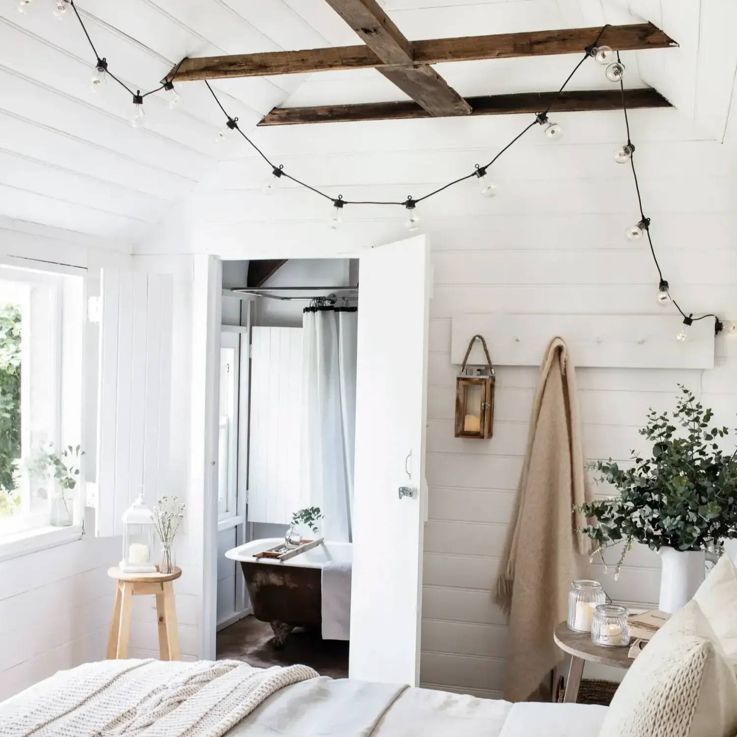 Bedroom featuring string lighting across the ceiling, with candles and lanterns distributed throughout the room.