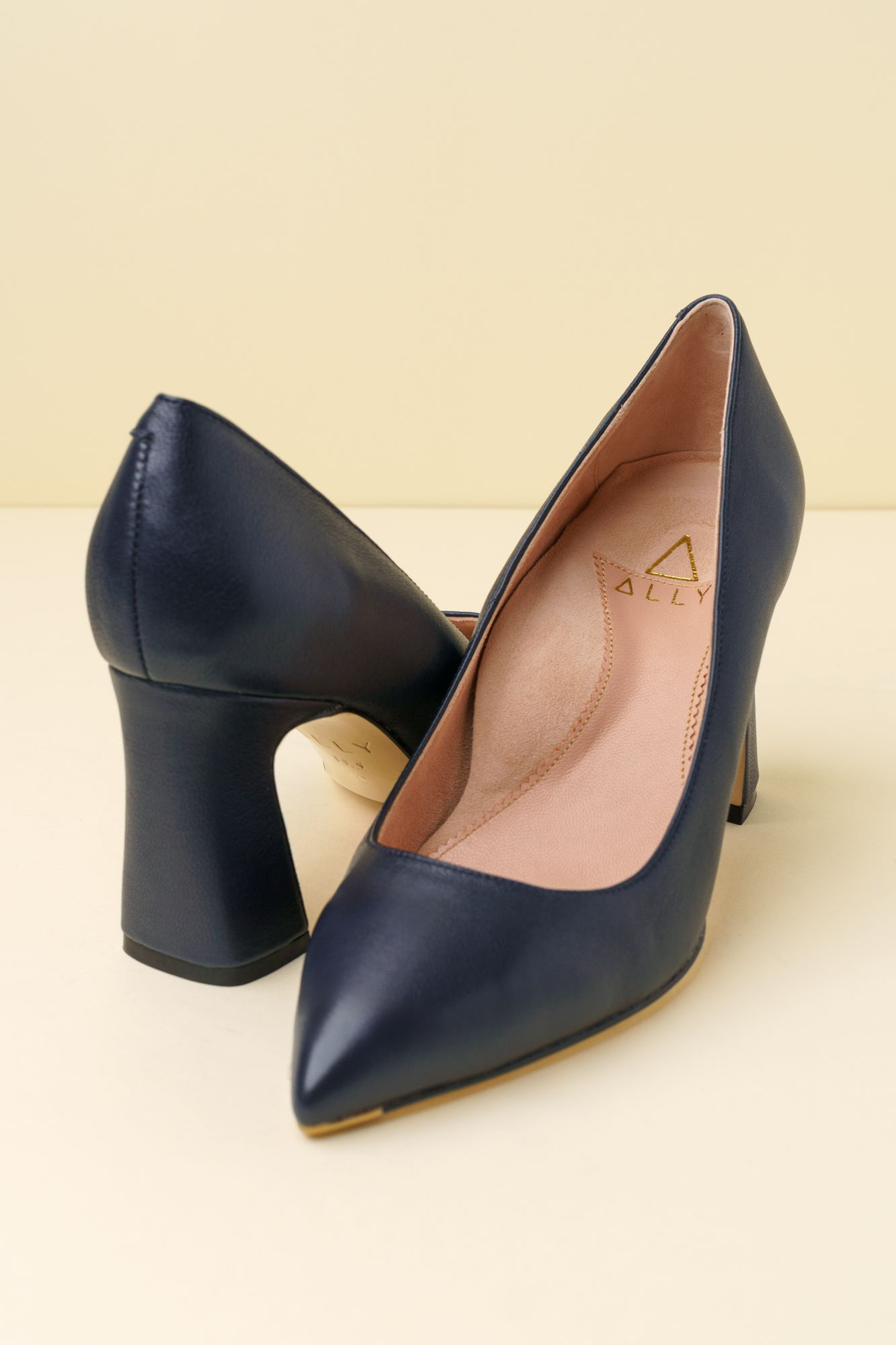 A pair of navy blue high-heeled shoes on a light background.