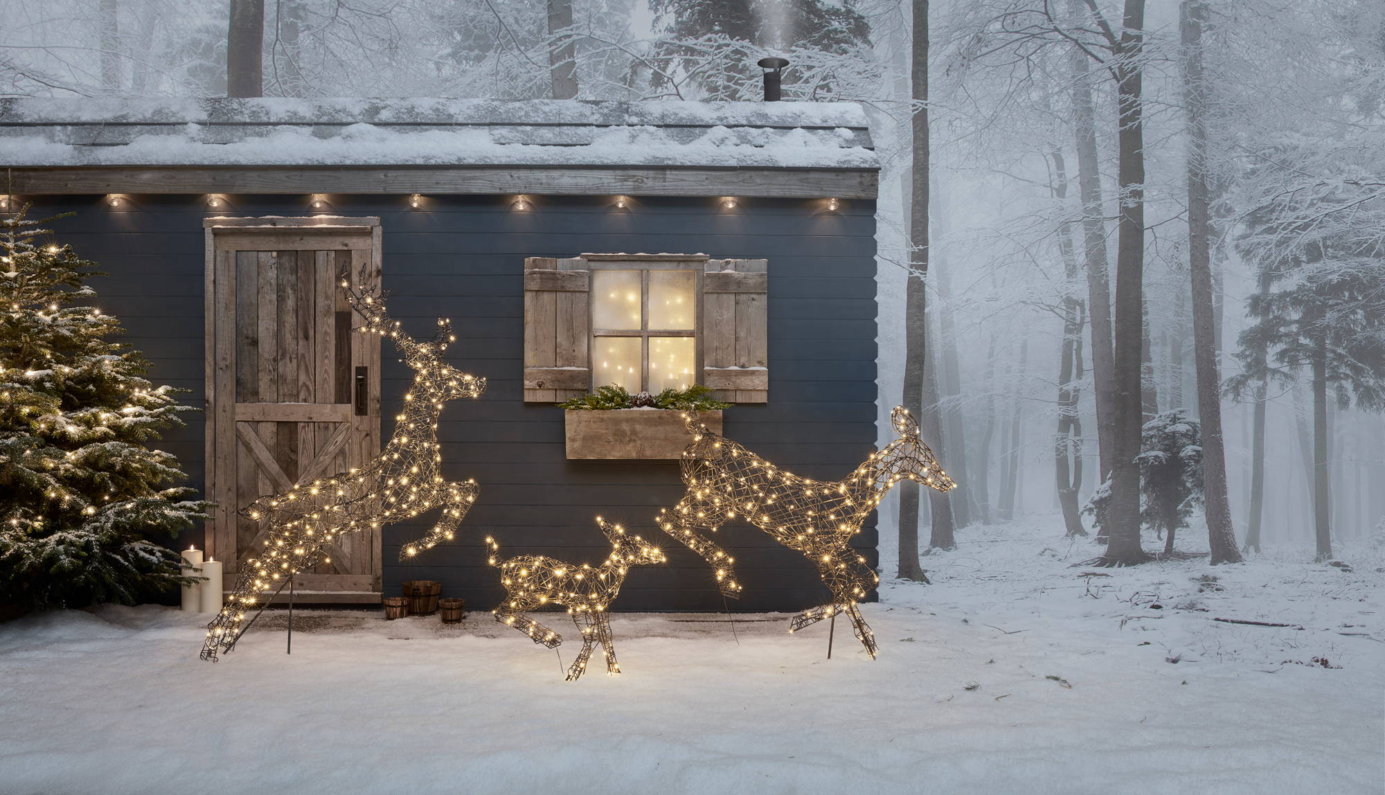 Family of rattan reindeer prancing in an outdoor snowy setting.