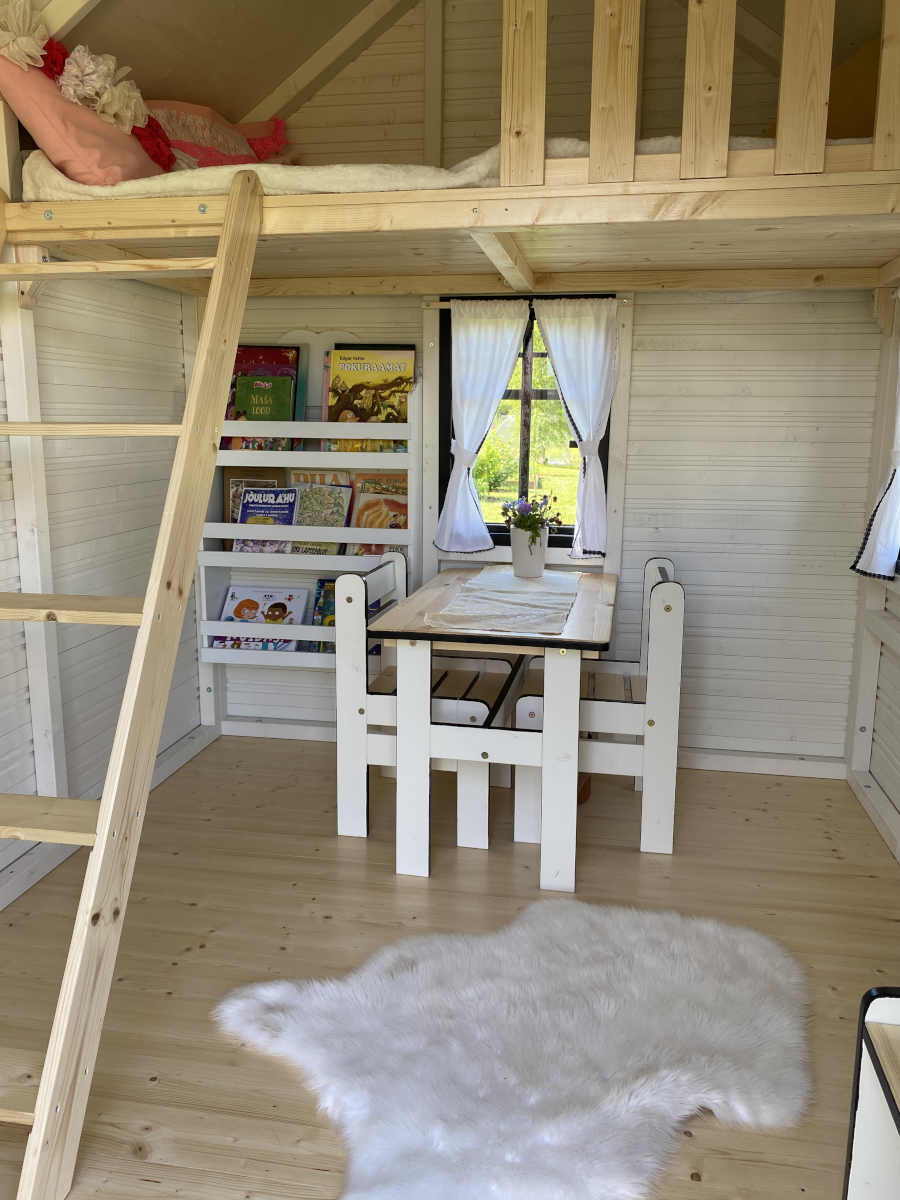 Inside of a decorated Custom Playhouse with loft and kids furniture by WholeWoodPlayhouses