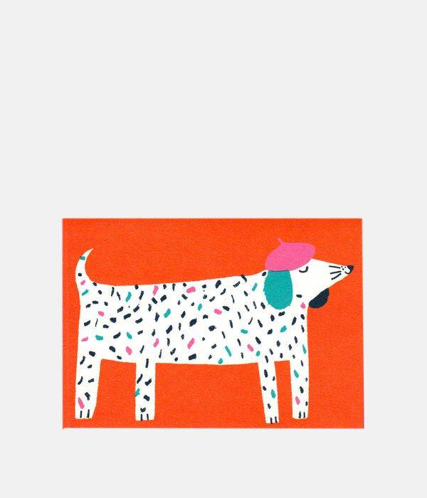 A greetings card with red background and a cartoon dog covered in black, pink and turquoise spots wearing a pink beret.