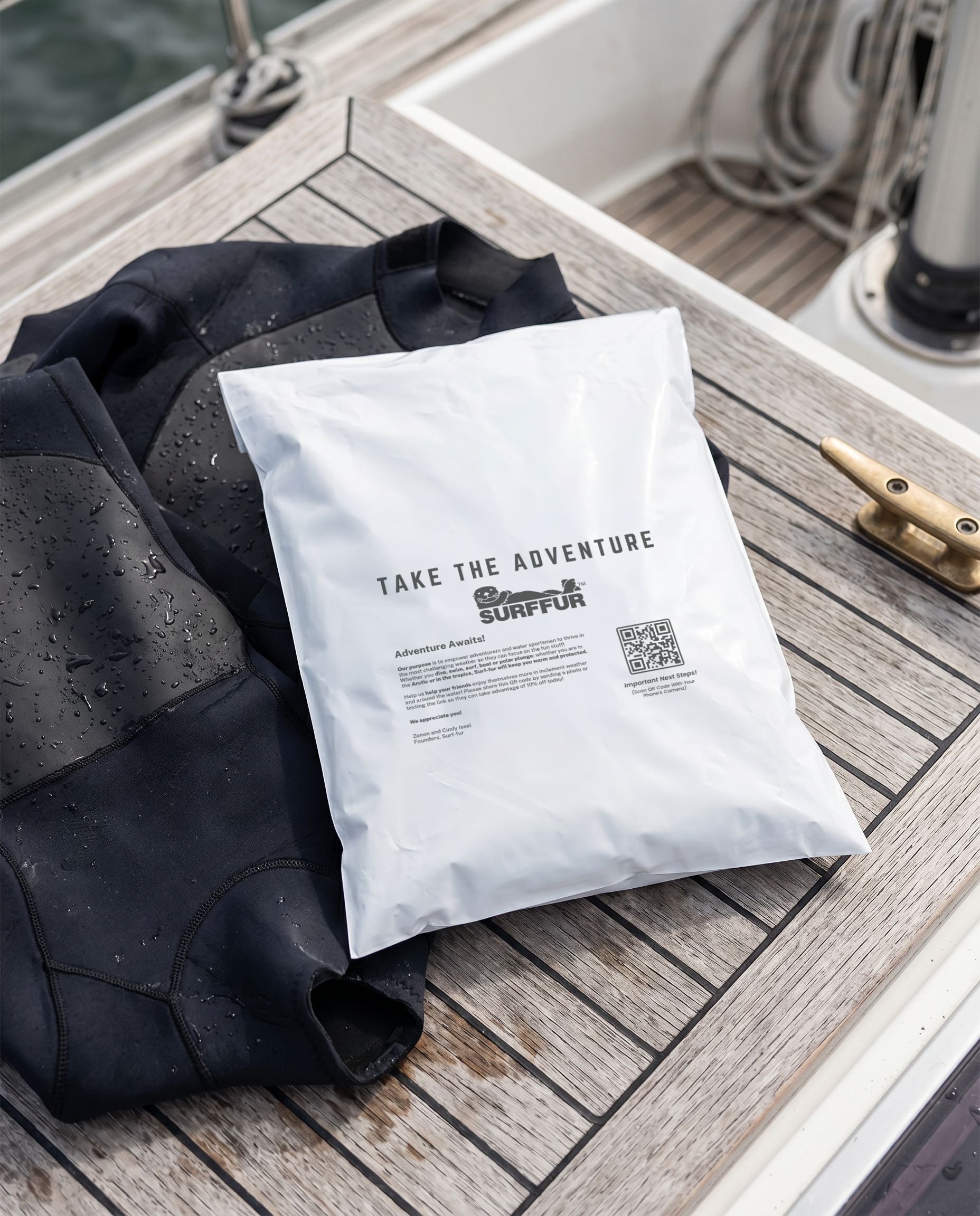White poly mailer on a wooden surface near black clothing on a boat.
